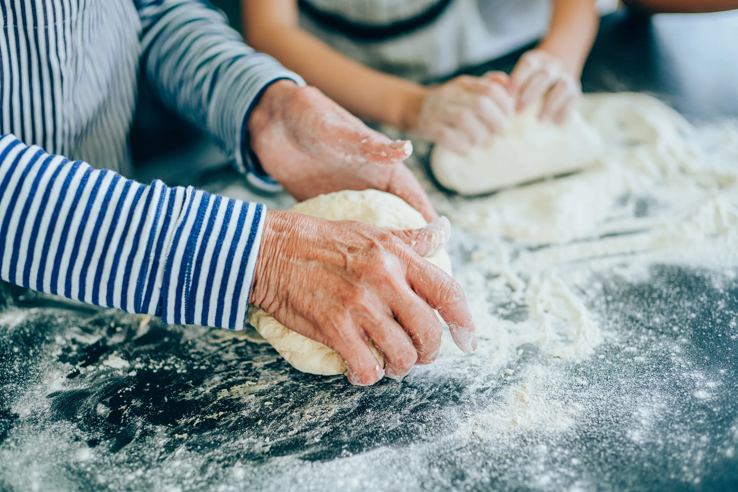 Grandparent and child kneading dough together
